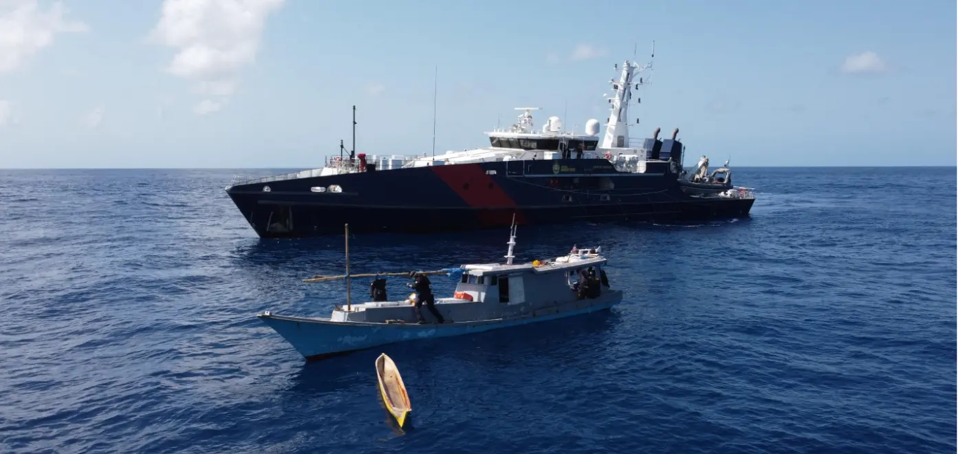 Large patrol vessel intercepting a small fishing boat in open ocean waters